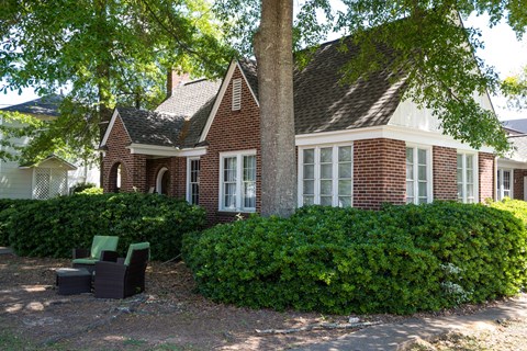 A red brick house with a white window and a green chair.