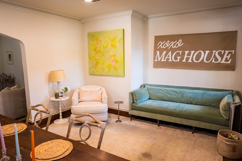 A living room with a green couch and a painting on the wall.