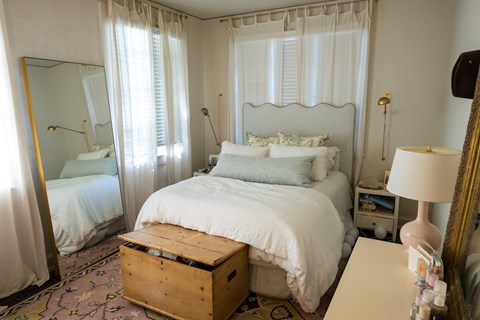 A bedroom with a large bed and a wooden trunk.