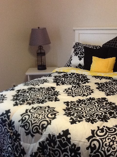 a bed with a black and white comforter and yellow pillows