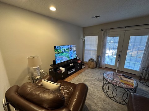 A living room with a brown leather chair and a flat screen TV.