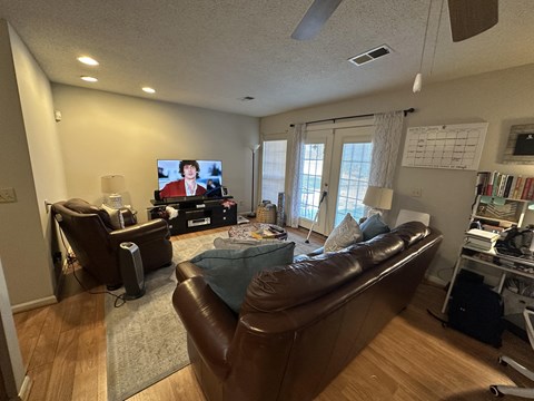 A living room with a brown couch and a television on the wall.