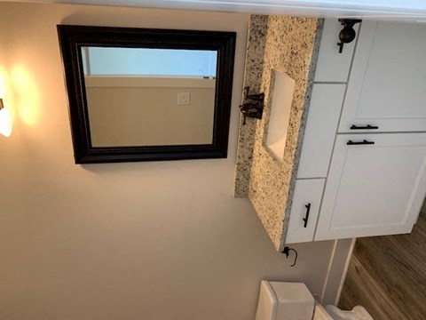 A bathroom with a toilet, a mirror, and a cabinet.