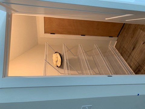 A white refrigerator with a single bag of bread on the bottom shelf.
