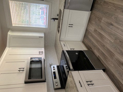 A modern kitchen with white cabinets and a black countertop.
