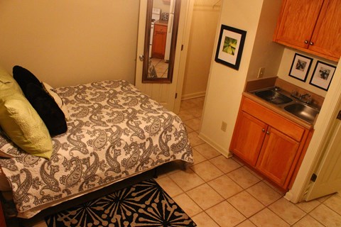A bedroom with a patterned bedspread and a green pillow.