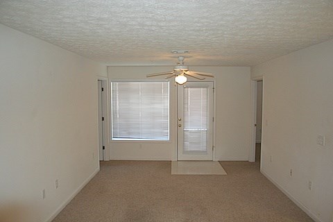 A room with a ceiling fan and a window with blinds.