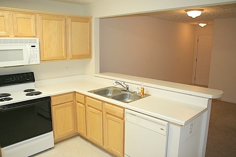 A kitchen with wooden cabinets and white appliances.