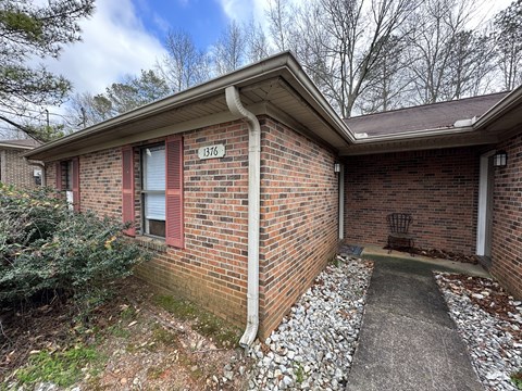 the side of a brick house with a porch and a driveway