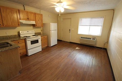 an empty kitchen with wooden floors and white appliances