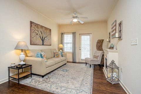 A living room with a beige couch, a chair, and a rug.