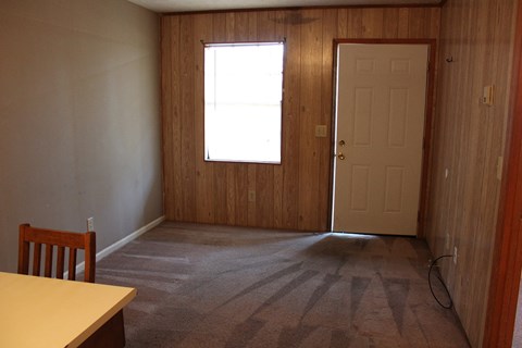 an empty living room with a door and a window