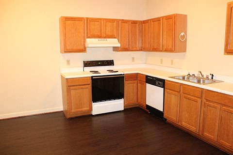A kitchen with wooden cabinets and a black dishwasher.