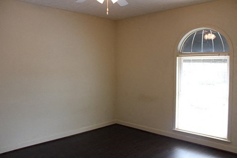 an empty living room with a large window and wooden floors