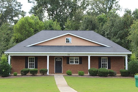 a brick house with a black roof and a sidewalk
