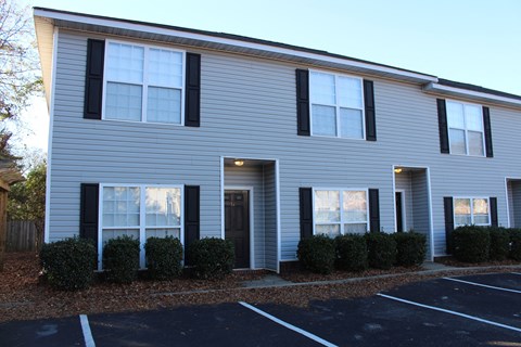 a white house with black shutters in a parking lot