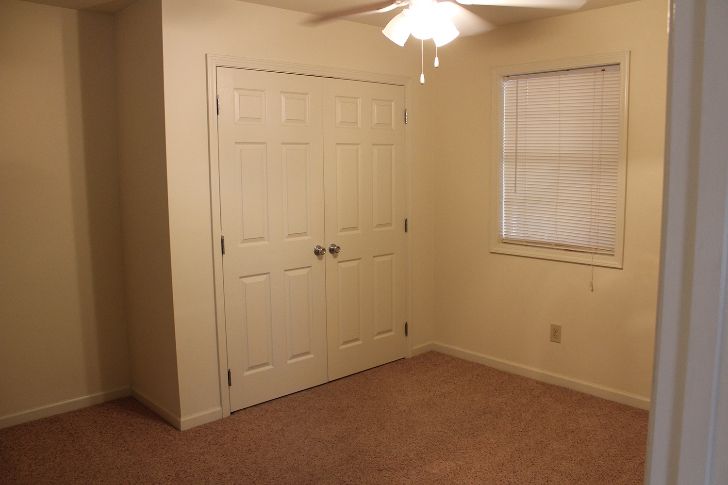 a bedroom with a door and a ceiling fan