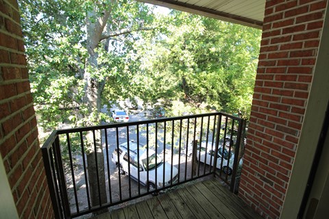 a balcony with a brick wall and trees