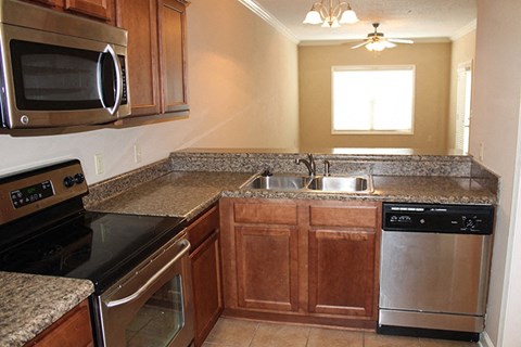 A kitchen with brown cabinets and granite countertops.