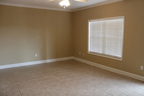 an empty living room with a window and tiled floor