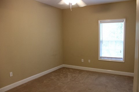 an empty living room with a window and carpet