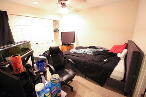 A bedroom with a bed, chair, and fish tank.