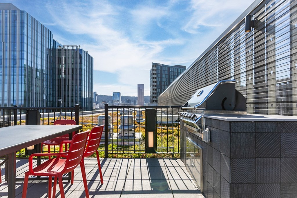 a rooftop patio with a grill and a table and chairs