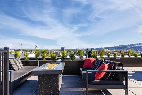 a rooftop terrace with chairs and a table and a view of the city