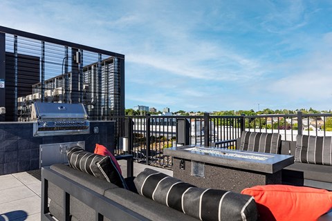 a rooftop patio with a grill and a table with chairs