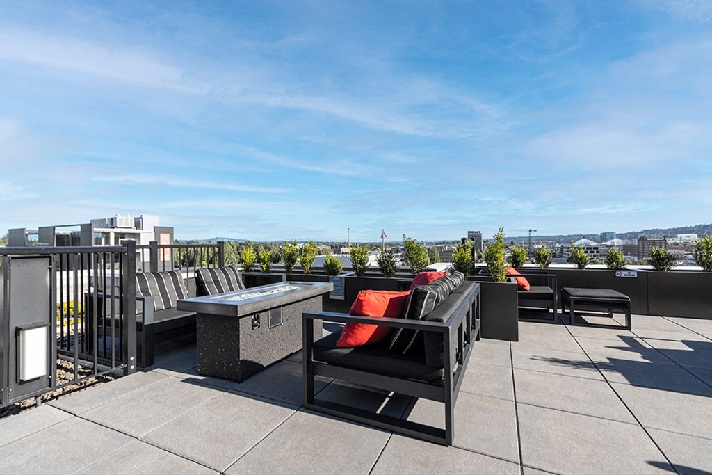 a rooftop terrace with chairs and a table and a view of the city