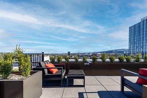 a rooftop patio with chairs and plants and a view of the city