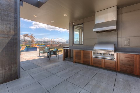 A kitchen with a grill and a table with chairs is seen from the inside of a building.