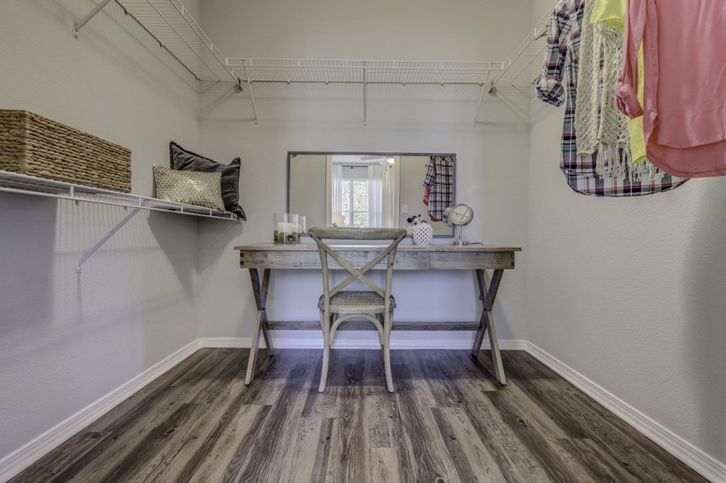 a vanity with a chair and a mirror in a room with a closet