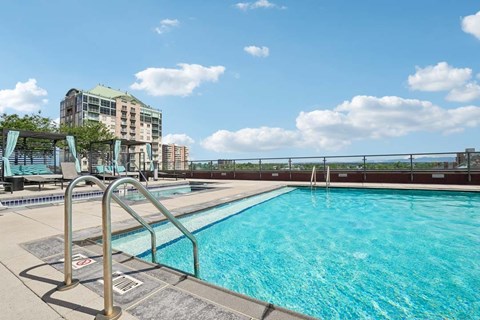 A swimming pool with a metal ladder and a building in the background.