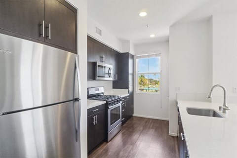 A modern kitchen with a stainless steel refrigerator and wooden floors.