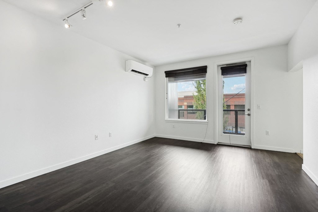 an empty living room with wood floors and a door to a balcony