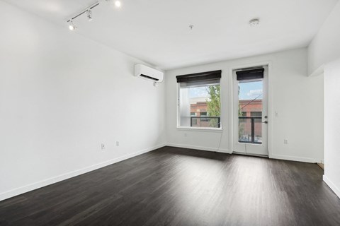 an empty living room with wood floors and a door to a balcony