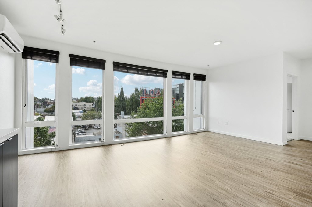 an empty living room with large windows and a wood floor
