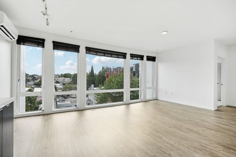 an empty living room with large windows and a wood floor