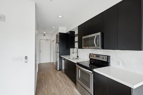 a kitchen with black cabinets and stainless steel appliances and white counter tops