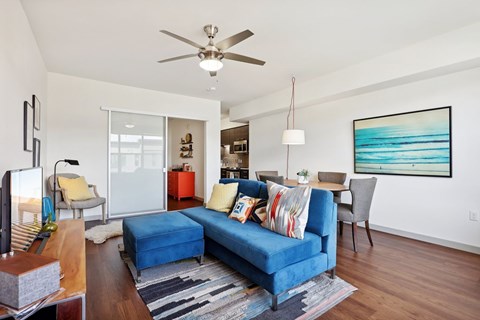 A living room with a blue couch and a ceiling fan.