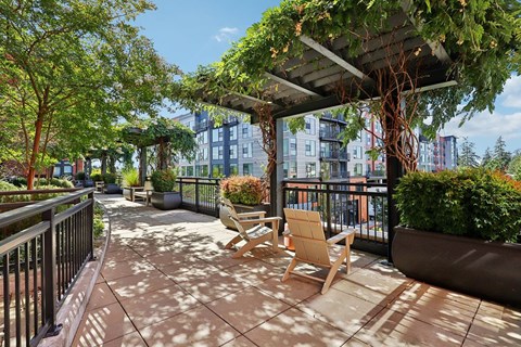A patio with a table and chairs under a trellis.