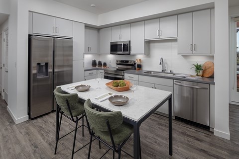 A modern kitchen with a table and chairs set for two.
