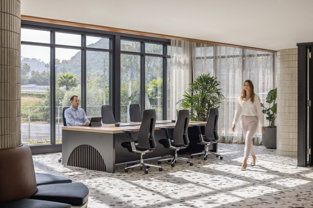 a woman walks through a meeting room with a desk and chairs