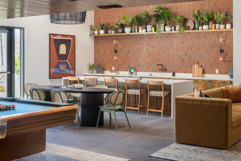 a communal area with a pool table and a bar with chairs and a kitchen with