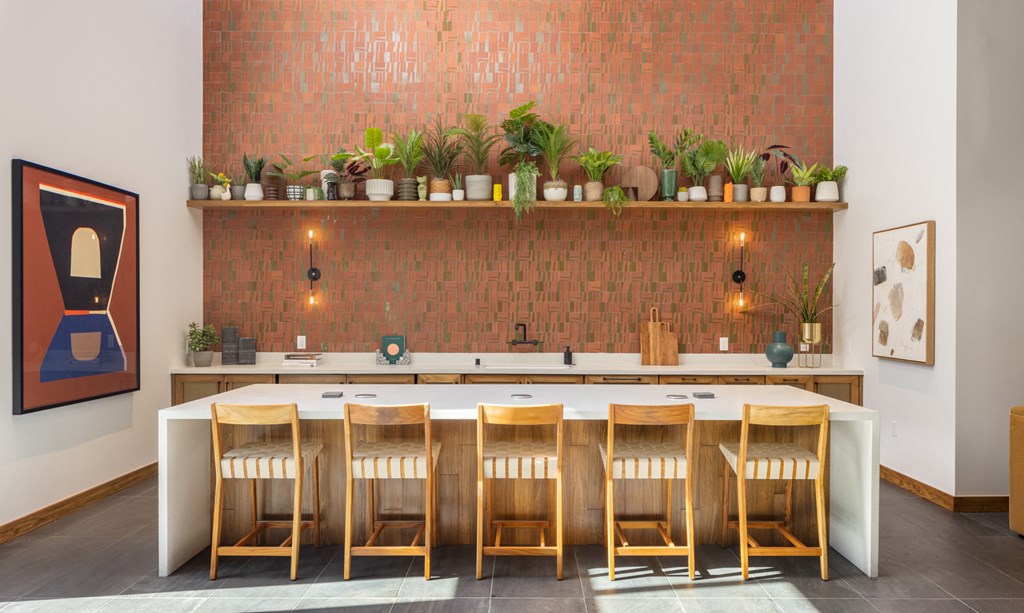a bar with wooden chairs and potted plants on a brick wall