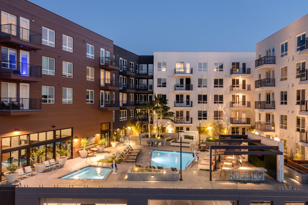 an apartment building with a swimming pool and a courtyard at night