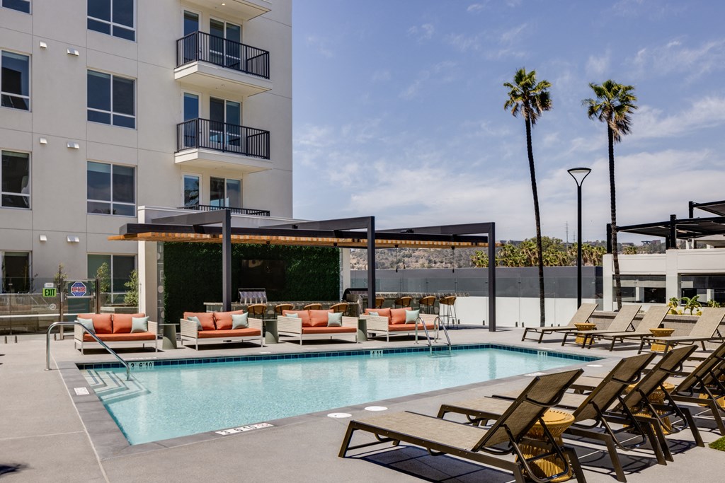 a swimming pool with lounge chairs and a building in the background
