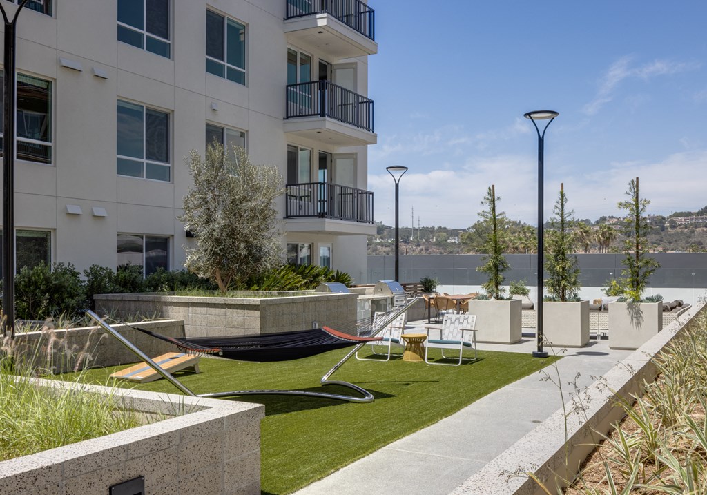 a yard with a hammock and chairs on a lawn in front of a building