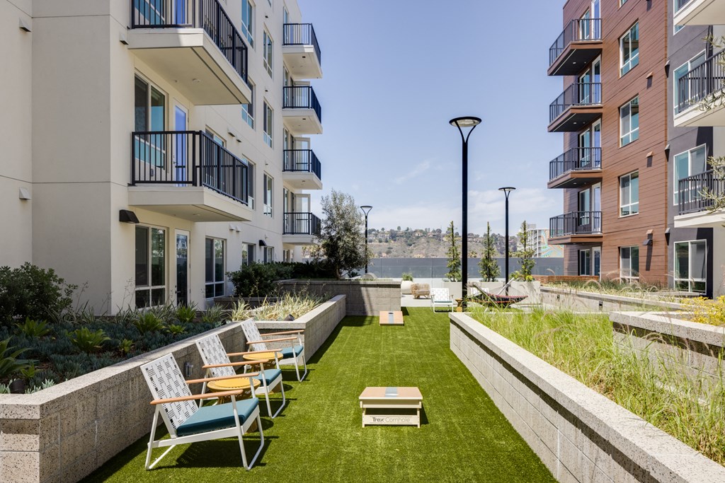 an apartment yard with lawn chairs and a view of the water
